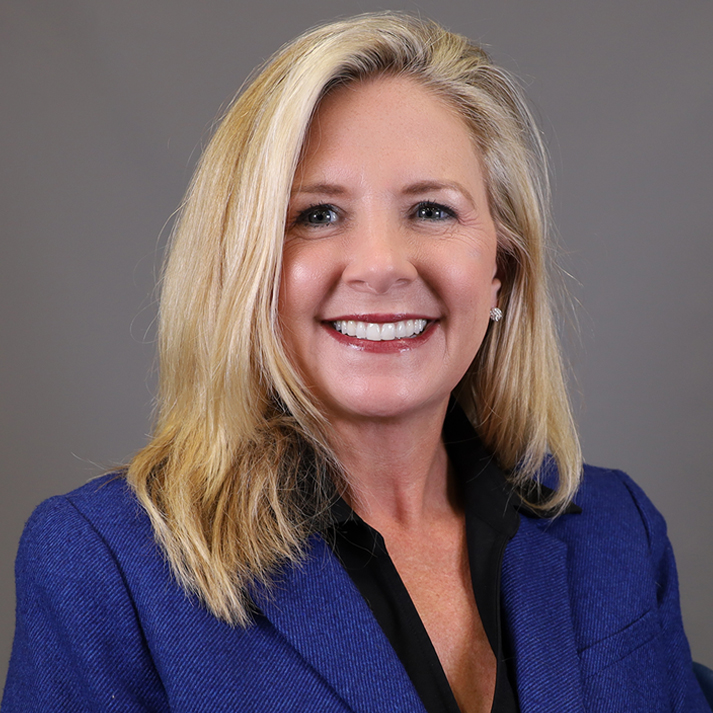 A light skin woman with medium length blonde hair, wearing a bright blue blazer.